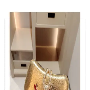 Gold evening clutch bag detail showing glittering rhinestone teardrop clasp and leather texture.