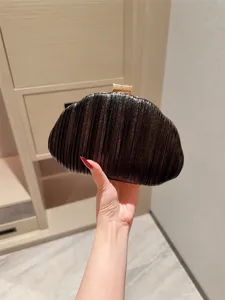 Elegant black pleated clutch evening bag held in hand, perfect for weddings and formal parties.