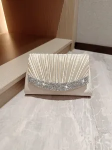 Elegant champagne pleated evening clutch bag with sparkling rhinestones for party events.