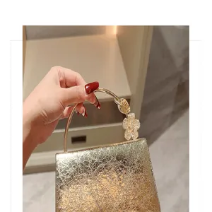 Detail shot of the gold metallic evening bag with sparkling rhinestone flower and ring handle.