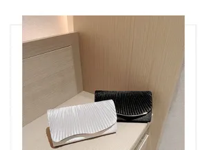 Detailed view of elegant satin pleated evening clutch bags in black and white for formal events.