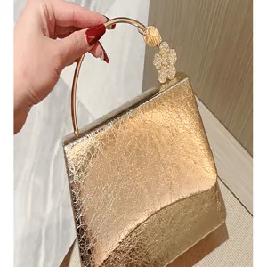 Gold metallic leather evening bag with circular metal handle and rhinestone flower detail.