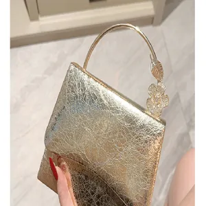Detail view of a glamorous gold evening bag with metallic ring handle and crystal flower.