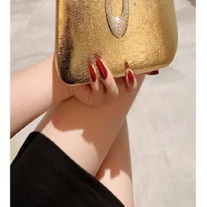 Detailed shot of gold evening clutch bag with sparkling rhinestone teardrop clasp.