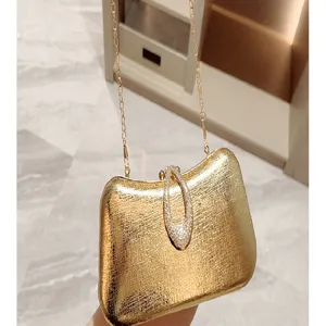 Gold leather evening bag detail, featuring sparkly diamond water drop clasp and metal chain.