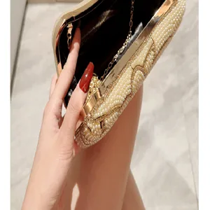 Close-up detail shot of vintage pearl beaded evening clutch bag with gold metal frame.