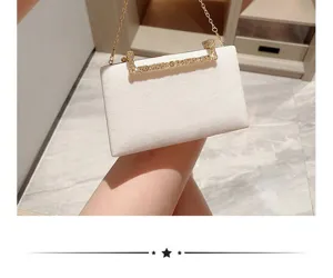 Detailaufnahme der weißen Samt Abendtasche mit funkelndem Strassverschluss und goldener Kette.