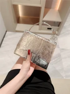 Glossy leather evening bag with metal round handle and rhinestone flower charm for party.