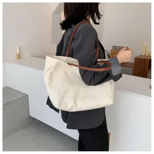 Vue latérale détaillée d'un grand sac cabas en toile blanche poignées marron clair.