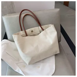 Vue détaillée du sac cabas en toile beige avec anses en cuir marron, style décontracté et épuré.