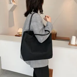 Sac cabas en toile noire minimaliste pour femme, grand sac porté épaule pour usage quotidien.