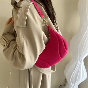 Detailed view of the bright pink hobo shoulder bag with unique pleated texture and metal hardware.
