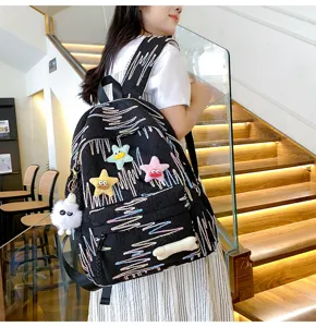 Cute sweet style black backpack detail showing colorful embroidery and plush pendant.
