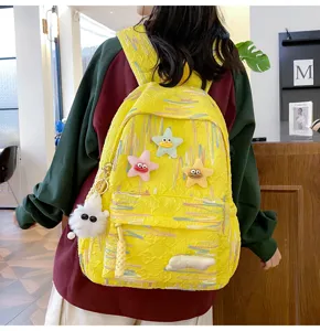 Cute yellow backpack detail showing plush star charms, colorful streaks and soft fuzzy toys.