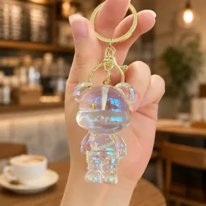 Clear closeup of transparent iridescent bear keychain with gold clasp, cute bag pendant charm.
