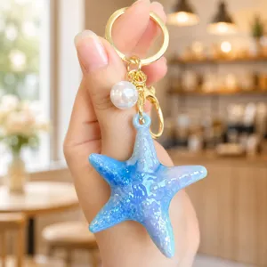 Closeup of the blue starfish keychain with pearl detail, highlighting acrylic texture and gold ring.
