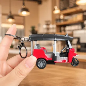 Dettaglio ravvicinato di un portachiavi creativo in miniatura tuk-tuk a tre ruote con anello.