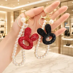 Nahaufnahme zeigt Strass Kaninchen Kopf Schlüsselanhänger mit eleganter Perlenkette und Metallclip.