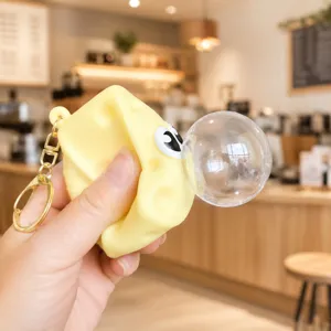 Yellow cheese squeeze toy keychain with cute cartoon eyes and simulation bubble for kids gifts.