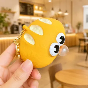 Close-up detail of yellow squeeze toy keychain with big eyes and bubble design.