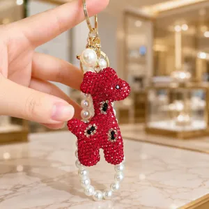 Detailed view of a sparkly red crystal giraffe keychain with elegant pearl string design.