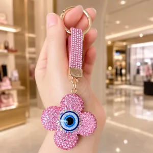 Vue détail porte-clés trèfle strass rose avec pendentif œil maléfique étincelant pour sac élégant.