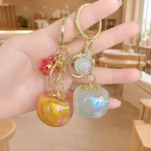 Close-up detail of glossy persimmon keychain, cute acrylic fruit bag charm pendant.