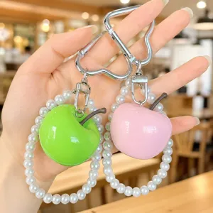 Close-up detail of simulation apple keychain with pearl bracelet and heart carabiner.