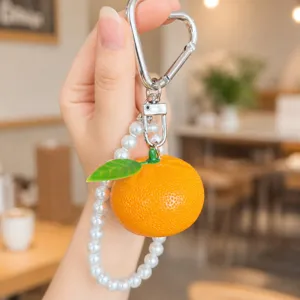 Detailed close-up showing the cute resin orange pendant with a pearl strap and metal hook.