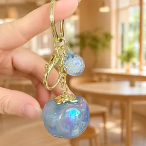 Close-up detail of the iridescent blue acrylic persimmon keychain with gold metal hardware.