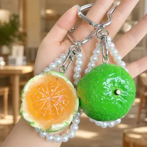 Nahaufnahme des kreativen geschälten Orangen und Limetten Frucht Schlüsselanhängers mit Perlen.