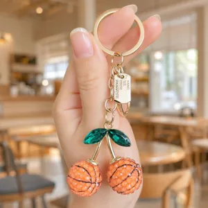 Chic basketball cherry keychain with green crystal leaves and gold hardware for bags.