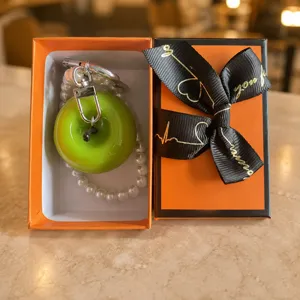 Resin green apple pearl keychain detail view, cute fruit pendant in luxury orange gift box.