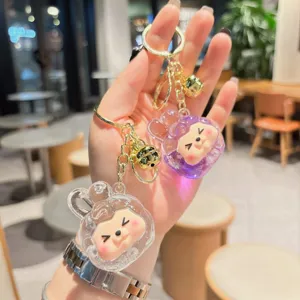 Cute liquid quicksand acrylic keychain with cartoon bear character charm and gold bells pendant for bags.