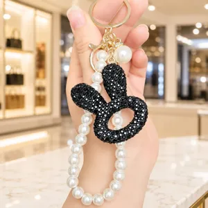 Nahaufnahme des luxuriösen schwarzen Strass-Hasen-Schlüsselanhängers mit eleganter Perlenkette.