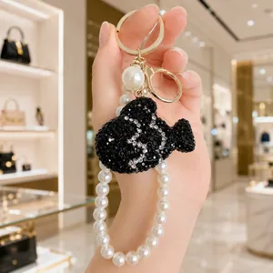 Detailed close-up of the elegant black crystal fish keychain with pearl strap design.