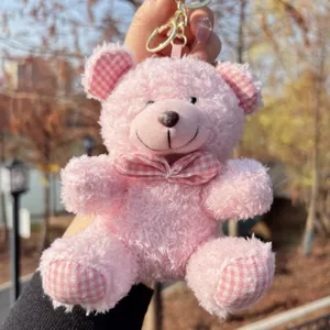 Plush pink teddy bear keychain detail with cute plaid bow, soft toy bag pendant accessory.