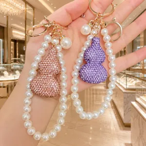 Detailaufnahme des funkelnden Strass-Kürbis-Schlüsselanhängers mit Perlenkette.