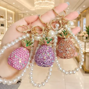 Close-up detail of sparkling rhinestone pineapple keychain with pearl wrist strap accessory.