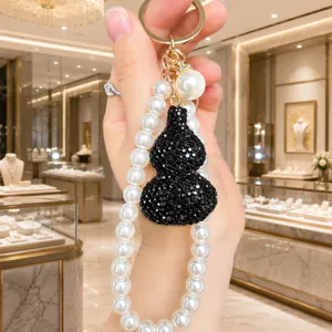 Detailansicht des glitzernden schwarzen Strass-Kürbis-Schlüsselanhängers mit Perlenkette.