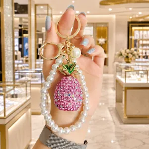 Sparkling pink crystal pineapple keychain with elegant faux pearl wrist strap accessory.
