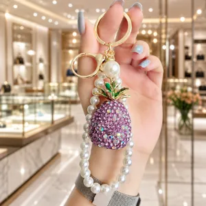 Close-up detail of the sparkling rhinestone pineapple pendant with elegant pearl strap design.