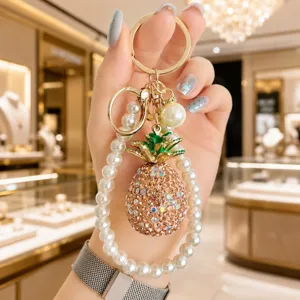 Detailed close-up of a luxury rhinestone pineapple keychain with elegant pearl strap charm for bags.