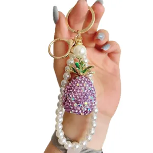 Luxury rhinestone pineapple keychain with pearl strap, sparkling crystal fruit bag charm for women.