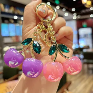 Detail shot of stylish cherry keychain with colorful crystal leaves for bags and keys.