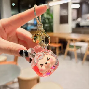 Close-up transparent acrylic quicksand keychain with glitter and cute cartoon character pendant.