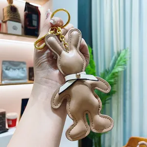 Close-up of cute PU leather rabbit keychain with bow tie, detailed hanging bag charm pendant.
