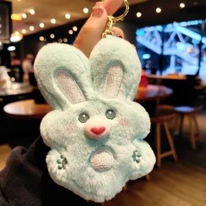 Close-up detail of cute mint green plush rabbit keychain with cute embroidered face and key ring.