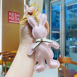 Cute pink PU leather rabbit keychain with white bow and gold hardware, ideal bag charm gift.