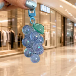 Close-up detail of a translucent blue acrylic grape keychain with green leaf bag charm pendant.